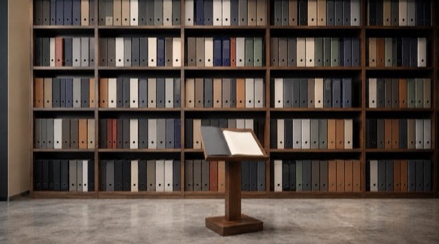 Kurs-Titelbild KI in Buchhaltung und Finanzen: Regalwand mit vielen gleichartigen Aktenordnern, davor ein Lesepult mit aufgeschlagener Mappe (KI-generiert)
